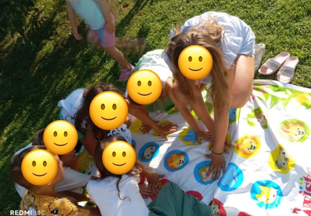 Djeca igraju Twister na velikom šarenom podlošku na travi